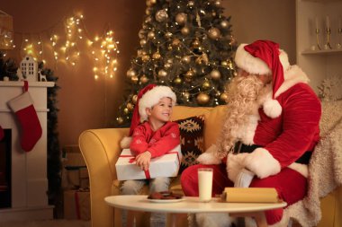 Noel hediyesi olan şirin küçük bir çocuk ve evde Noel Baba.