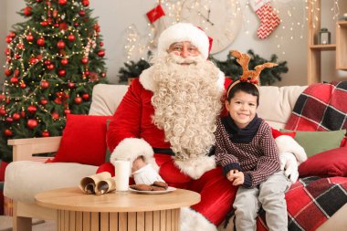 Noel Baba ve Noel arifesinde evde ren geyiği boynuzları takan sevimli küçük çocuk.