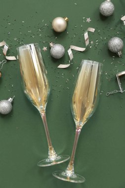 Yeşil arka planda Noel dekoru olan şampanya kadehleri.
