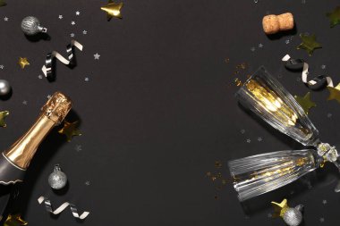 Gözlüklü şampanya şişesi ve siyah arka planda Noel süsü.