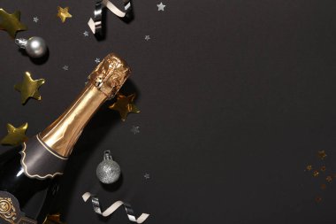Siyah arka planda Noel dekoru olan şampanya şişesi.