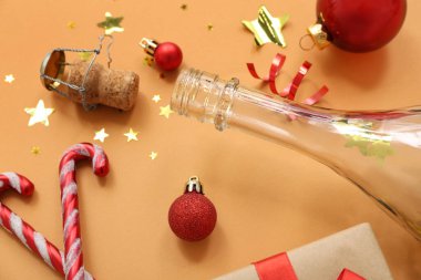Turuncu arka planda Noel dekoru olan şampanya şişesi.