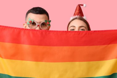 Pembe arka planda LGBT bayrağı olan genç çift