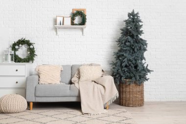 Gri kanepesi, beyaz çekmeceleri ve Noel ağacı olan şenlikli oturma odasının içi.
