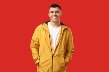 Kırmızı arka planda şık ceketli genç adam.