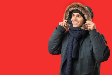 Kırmızı arka planda şık kabarık ceketli ve eşarplı genç adam.