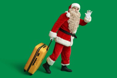 Yeşil arka planda el sallayan çantalı Noel Baba. Noel tatili konsepti