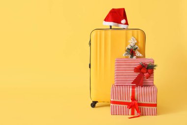 Sarı arka planda Noel Baba şapkalı ve Noel hediyeli çanta.