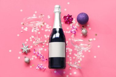 Gözlüklü bir şişe şampanya, Noel topları ve pembe arka planda konfeti.
