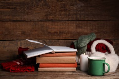 Kitaplı güzel kompozisyon, kış dekorasyonu, kalın kıyafetler ve kahverengi ahşap arka planda bir fincan kakao.