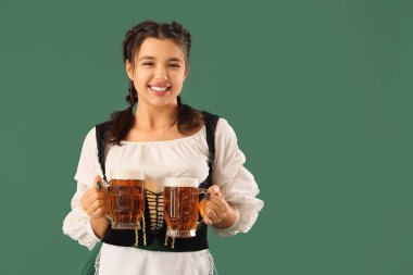 Yeşil arka planda birası olan genç Ekim Festivali garsonu.