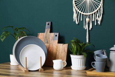 Mutfaktaki yeşil duvarın yanında bitkilerle dolu temiz tabaklar.