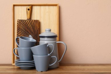 Bej duvarın yanındaki masada kesme tahtası olan temiz tabaklar.