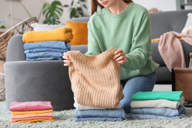 Evde temiz giysileri katlayan genç bir kadın.