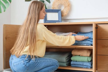 Güzel genç bir kadın evdeki dolabına temiz giysiler koyuyor.