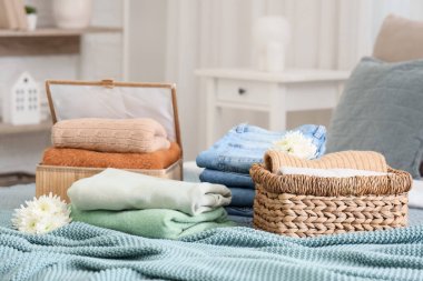 Hasır sepetler, şık giysiler ve yataktaki çiçekler.