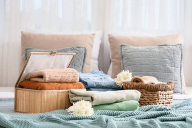 Hasır sepetler, şık giysiler ve yataktaki çiçekler.