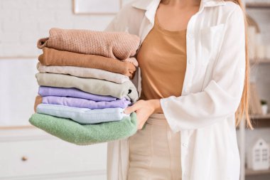 Evde şık giysileri olan genç bir kadın, yakın plan.