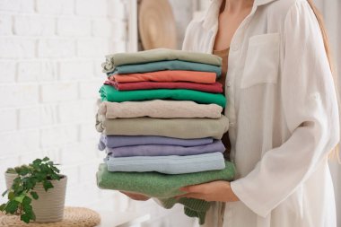 Evde şık giysileri olan genç bir kadın, yakın plan.