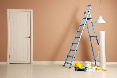 Boya kutularıyla merdiven, bej duvarın yanında baloncuk ambalajı.