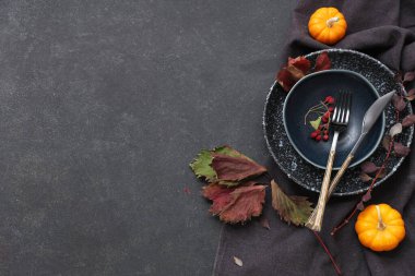 Taze balkabakları, gül kalçası böğürtlenleri ve siyah arka planda sonbahar yapraklarıyla güzel bir masa.