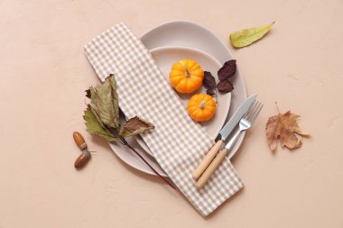 Taze balkabaklarıyla, meşe palamutlarıyla ve bej arka planda sonbahar yapraklarıyla güzel bir masa.