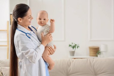 Female pediatrician holding little baby at home