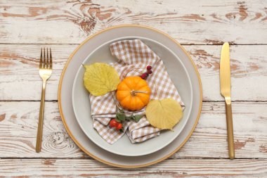 Altın çatal bıçak takımı ve hafif ahşap arka planda sonbahar dekoru olan güzel bir masa.