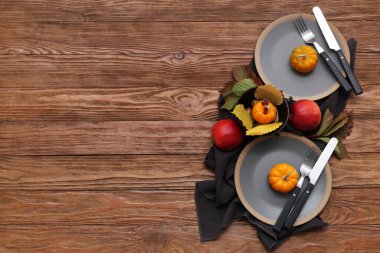 Ahşap arka planda balkabakları, elmalar ve düşen yapraklarla sonbahar masası.