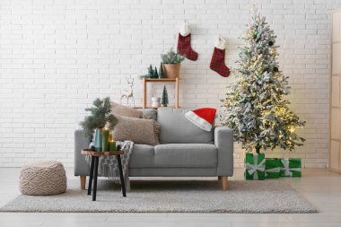 Gri kanepe, Noel ağacı ve kahve masasında yanan mumlarla dolu bir oturma odası.