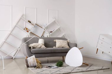 Gri kanepeli dağınık oturma odasının içi. Depremden sonra kahve masası ve raf üniteleri ters dönmüş.