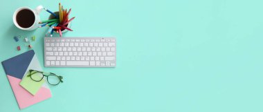 Grafik tasarımcısının PC klavyesi, turkuaz arka plan üzerinde kahve ve kırtasiyesi metin ve üst görünüm için alanı olan çalışma yeri