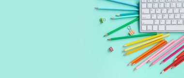 Grafik tasarımcısının PC klavyesi ve turkuaz arkaplan üzerindeki kırtasiyesi metin ve üst görünüm için alanı olan çalışma yeri