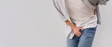 Gri arka planda prostat sorunu olan genç bir adam ve mesaj için yeri var. Prostat kanseri farkındalığı