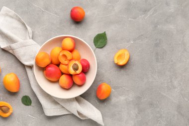 Gri arka planda tatlı kayısıları olan bir kase