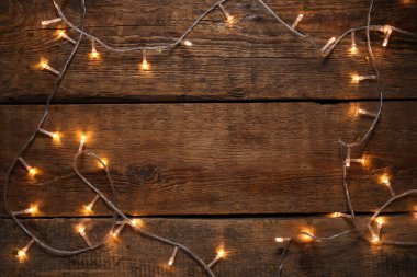 Ahşap arka planda parlayan Noel ışıklarından yapılmış çerçeve