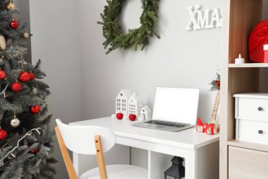 Ofisinde dizüstü bilgisayarı ve Noel dekoru olan bir işyeri