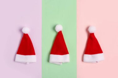 Renkli arka planda Noel Baba şapkaları