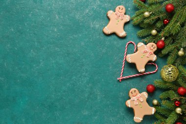 Noel tatlı zencefilli kurabiyeler, baston şekerler ve yeşil arka planda topları olan köknar dalları.