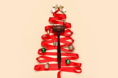 Kırmızı kurdeleden yapılmış Noel ağacı, yargıç tokmağı ve renk arkaplanındaki süslemeler