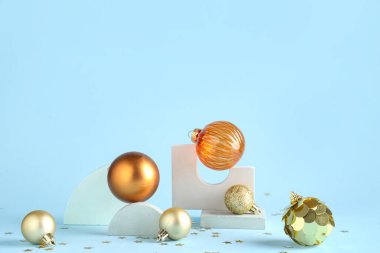 Dekoratif stantlar, farklı Noel topları ve mavi arka planda konfeti.