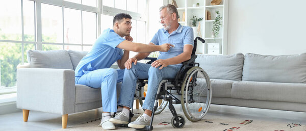 Male nurse hearing senior mans heartbeat in wheelchair at home