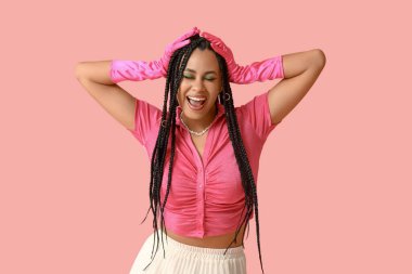 Pembe arka planda örgüleri olan şık duygusal Afro-Amerikan kadın.