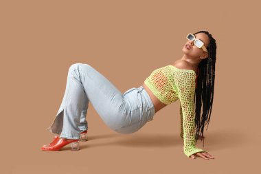 Bej arka planda örgüleri olan seksi Afro-Amerikalı kadın.