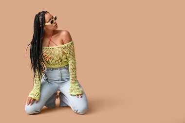 Bej arka planda örgüleri olan seksi Afro-Amerikalı kadın.