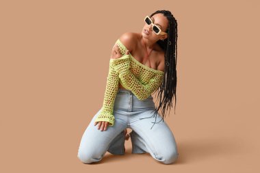 Bej arka planda örgüleri olan seksi Afro-Amerikalı kadın.