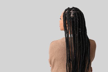 Beyaz arka planda örgüleri olan şık bir Afro-Amerikan kadın.