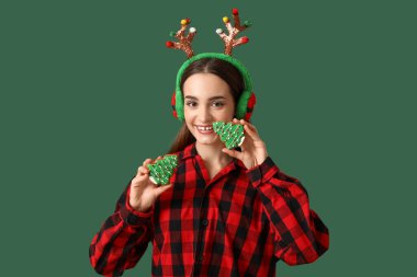 Yeşil arka planda lezzetli Noel kurabiyeli genç kadın.