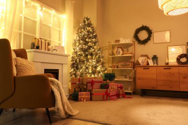 Işıl ışıl Noel ağacı, koltuk ve gece hediyeleri olan karanlık oturma odasının içi.
