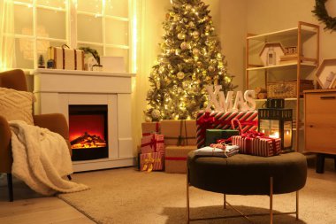 Parlayan Noel ağacı, hediyeler ve şöminesi olan karanlık oturma odasının içinde.